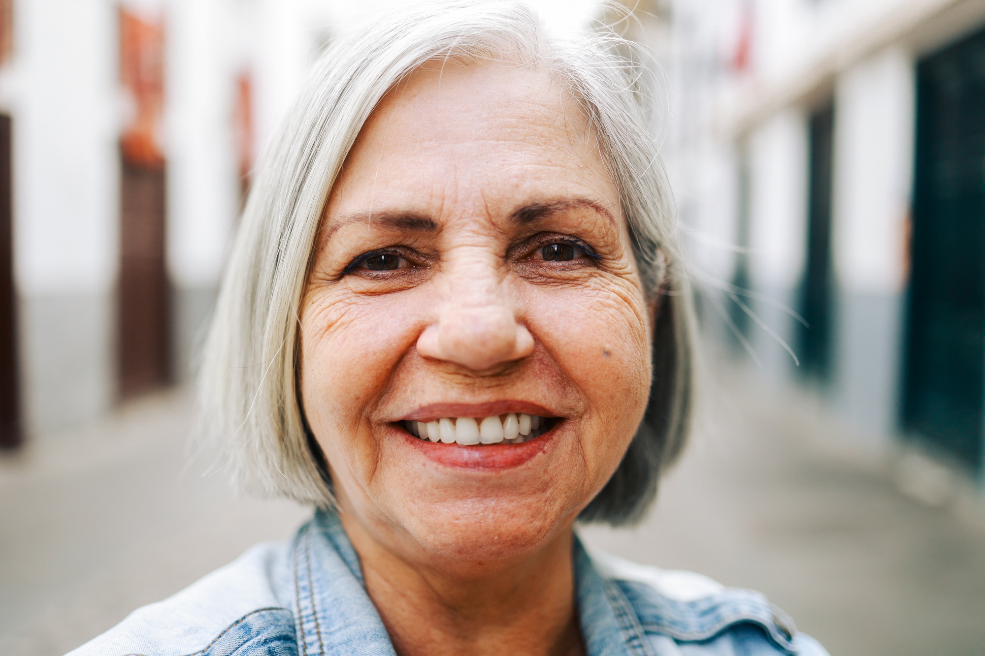 Happy senior woman looking at camera with city on background. Latin american older community concept