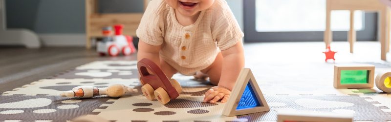 Cute happy baby boy playing toys in his child room
